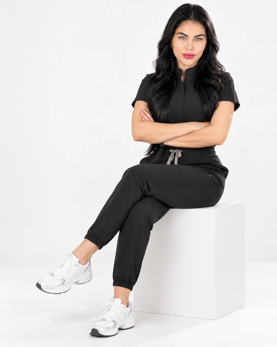 Camila, founder of LUNÉVIA, seated in black scrubs with her arms crossed.
